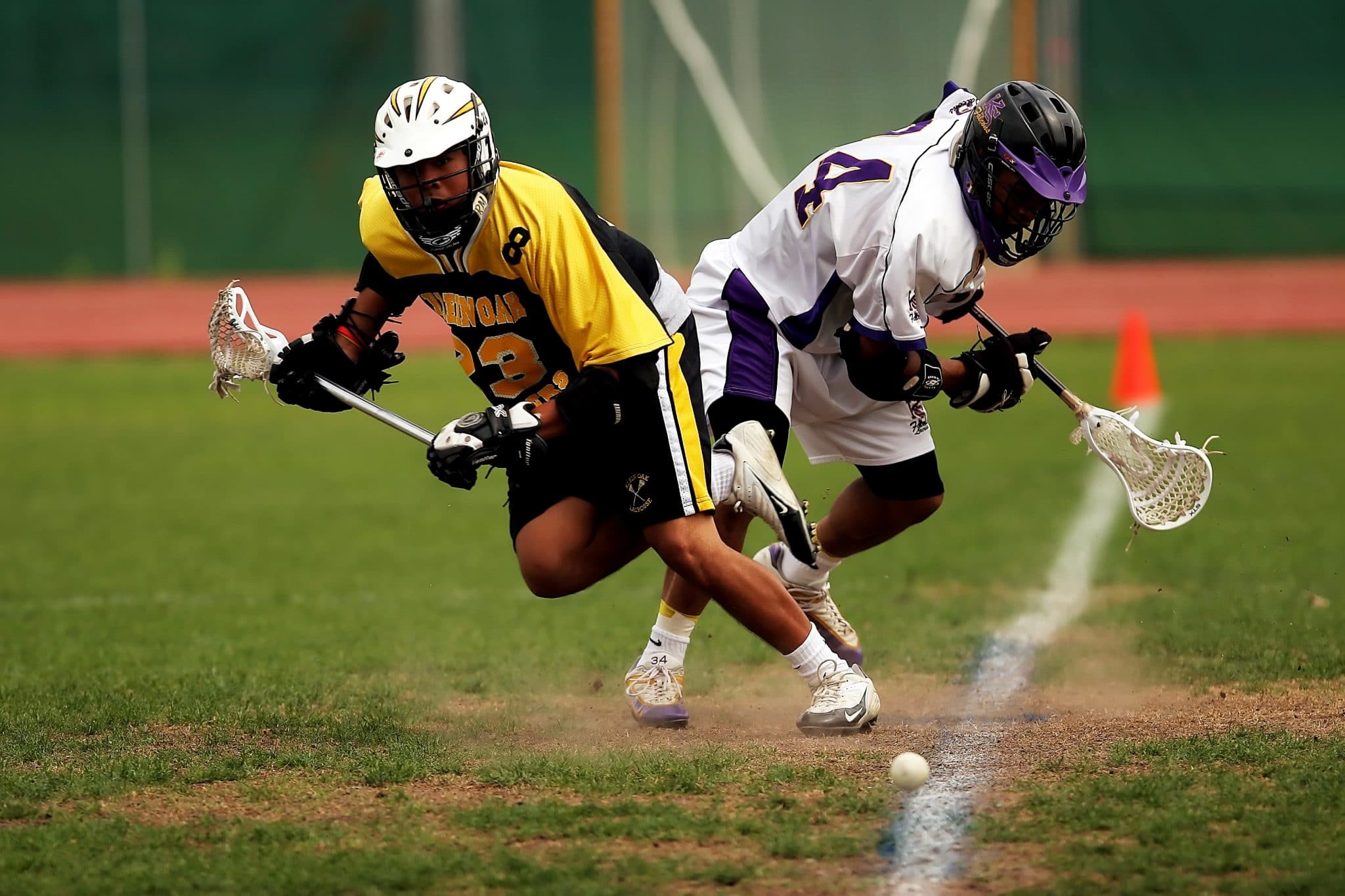 Man wearing yellow and black sport jersey holding lacrosse stick