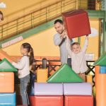 happy family with two children building castle with colorful blocks at game center