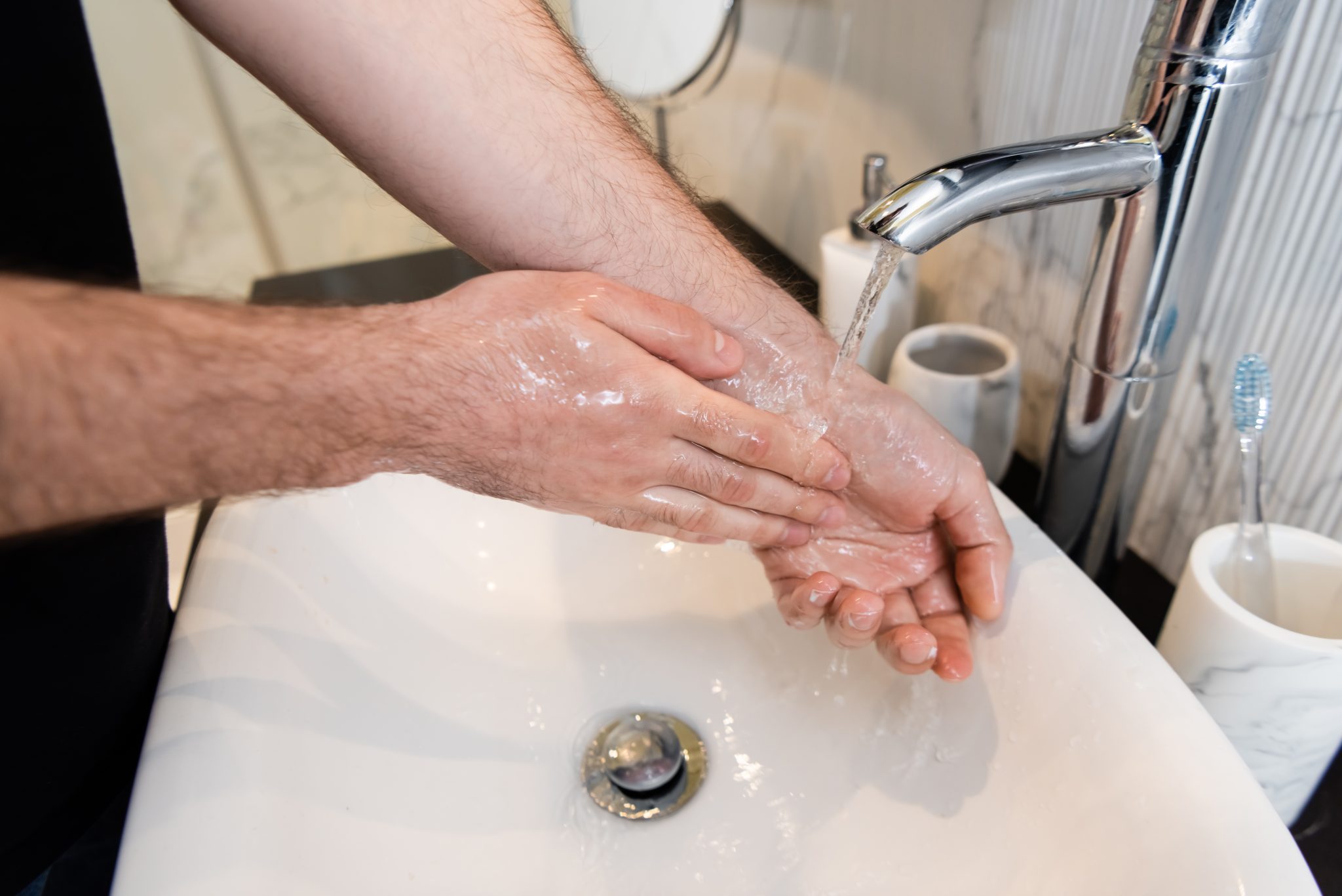 Cropped view of man washing hands in bathroom