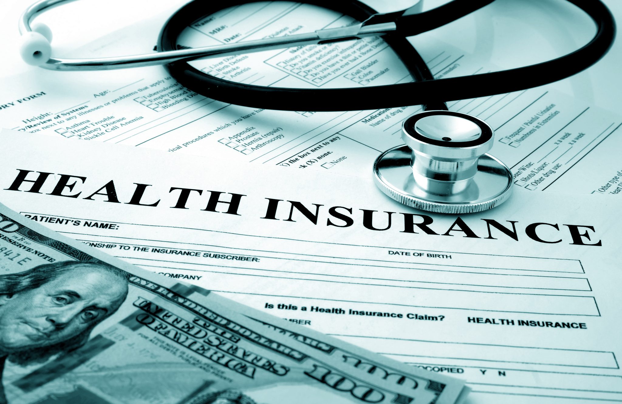 Health insurance form with dollars and stethoscope