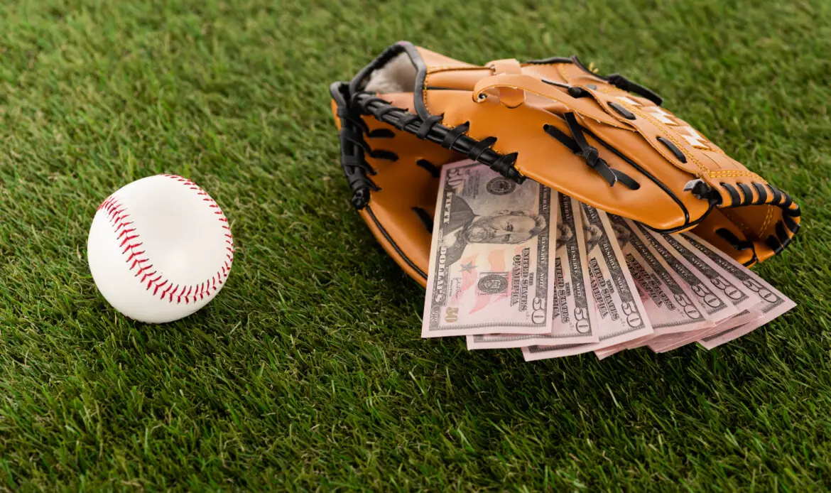 dollar banknotes in baseball glove near ball on green grass, sports betting concept