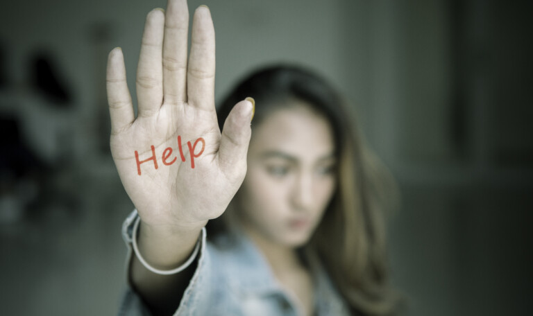 Teenage girl shows help word in dark room