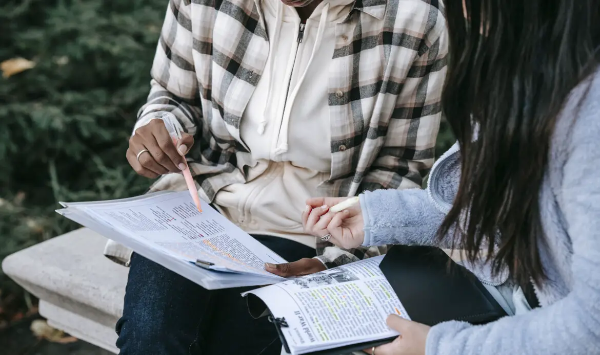 Crop focused students taking notes in papers