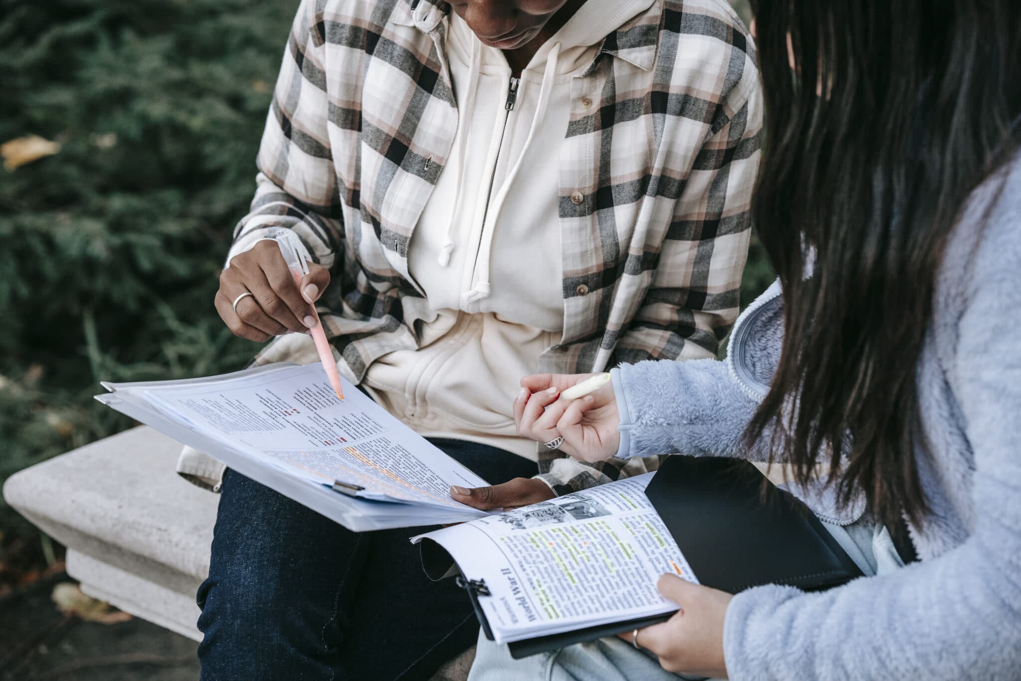 Crop focused students taking notes in papers