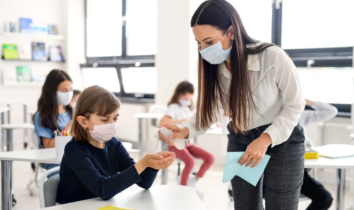 Teacher, children with face mask at school after covid-19 quarantine and lockdown.