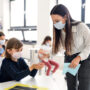 Teacher, children with face mask at school after covid-19 quarantine and lockdown.