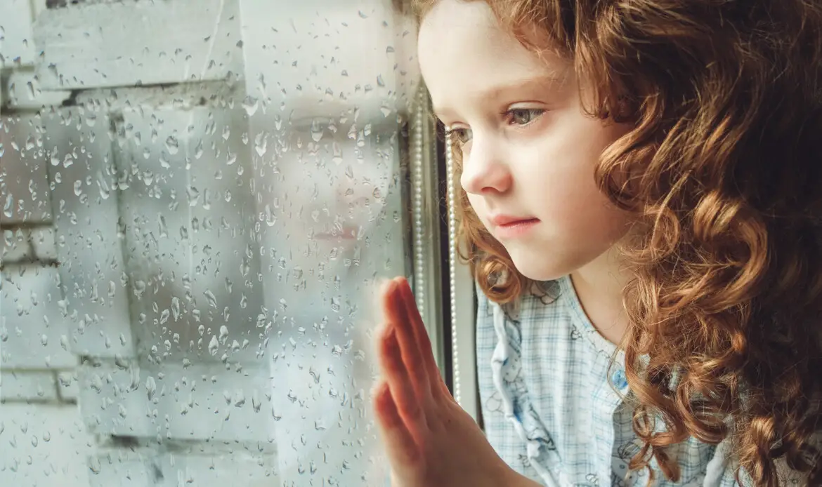 Sad child looking out the window. Toning photo.