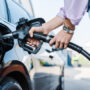 cropped view of woman holding fuel pump while refueling car with benzine
