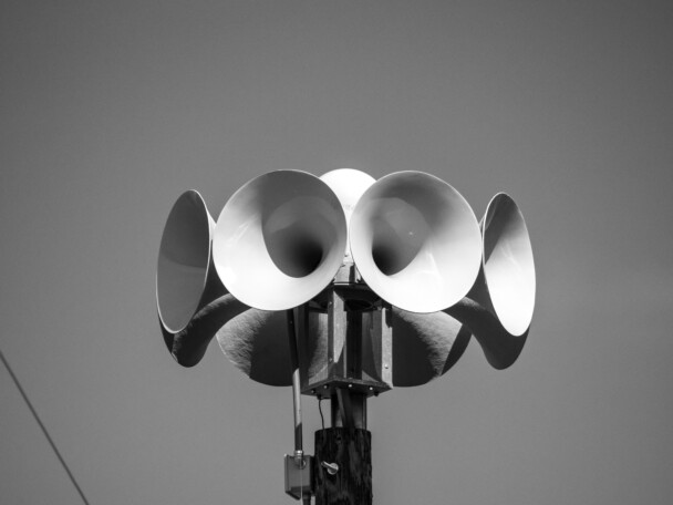 Close up photograph of several multi directional round amplified emergency siren or noon time horns on top of a wooden pole in a small town in Wisconsin.