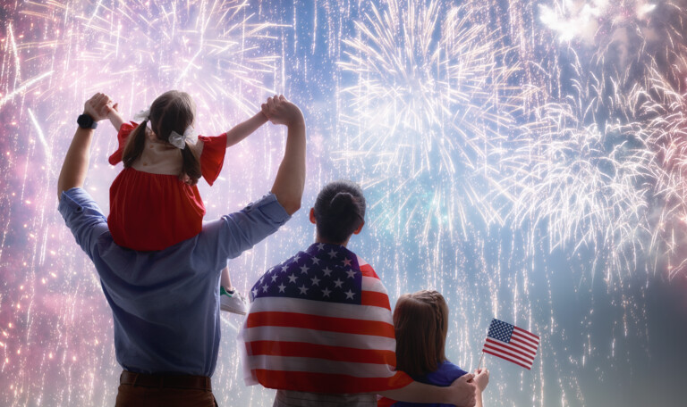 Patriotic holiday. Happy family, parents and daughter child girl with American flag outdoors. USA celebrate 4th of July.