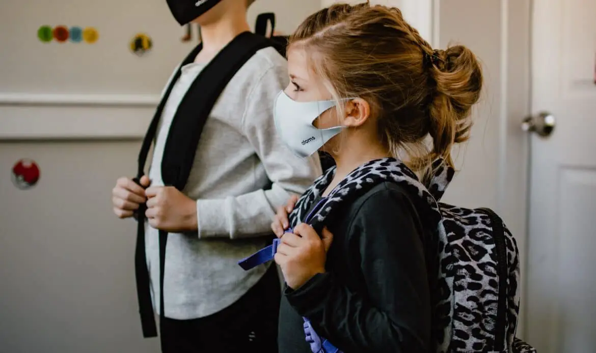 two kids standing side by side wearing masks