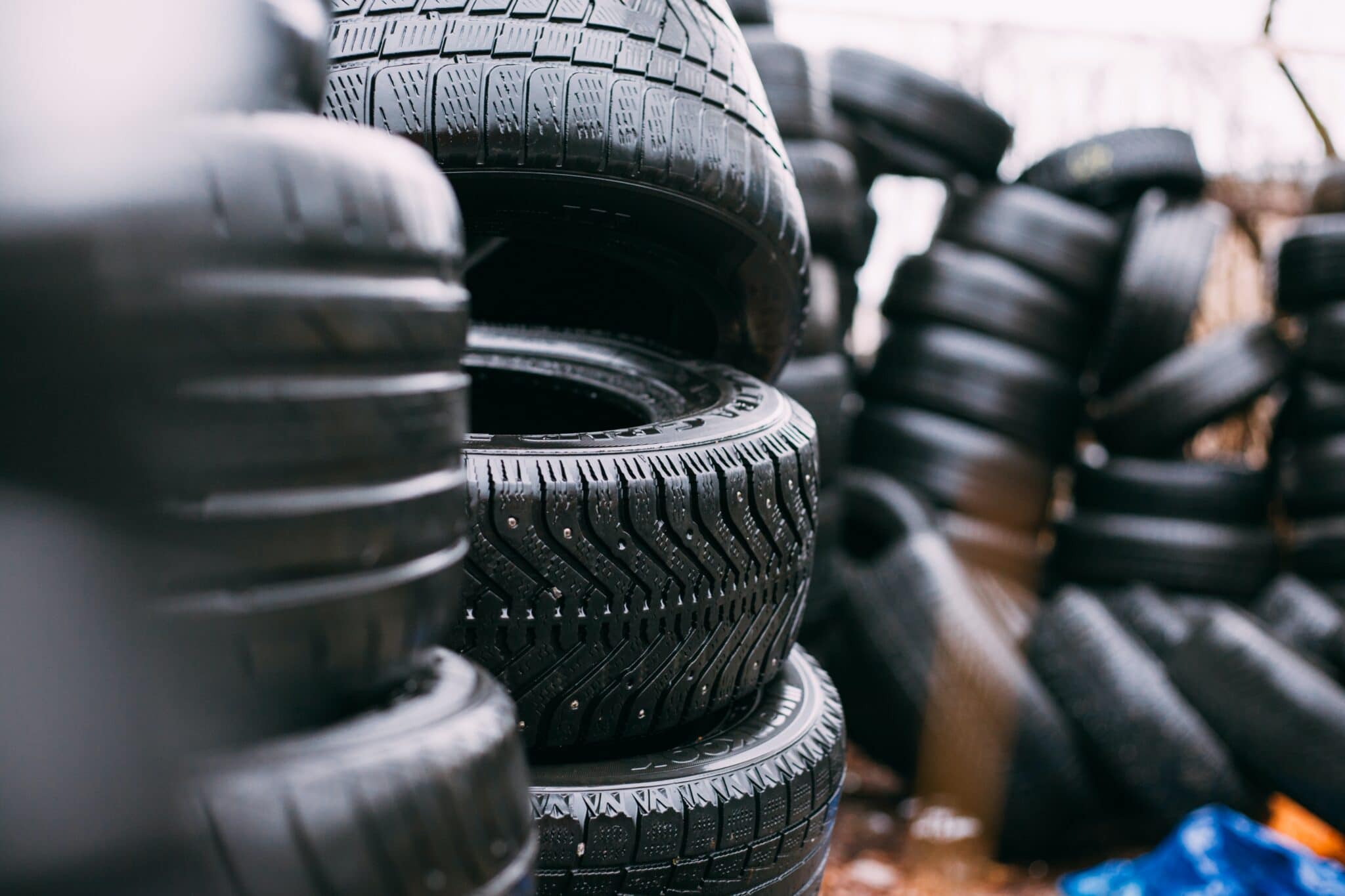 Pile of used tires. Daylight photo with minimum editing. Good for illustration in different kinds of automotive editorials. Model in the center is Goodyear Ultra Grip studded winter tire.