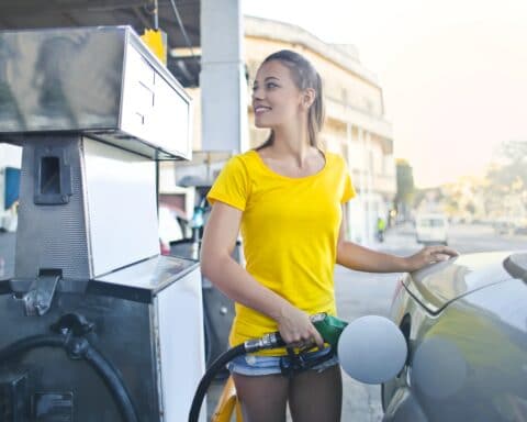Woman in yellow shirt while filling up her car with gasoline