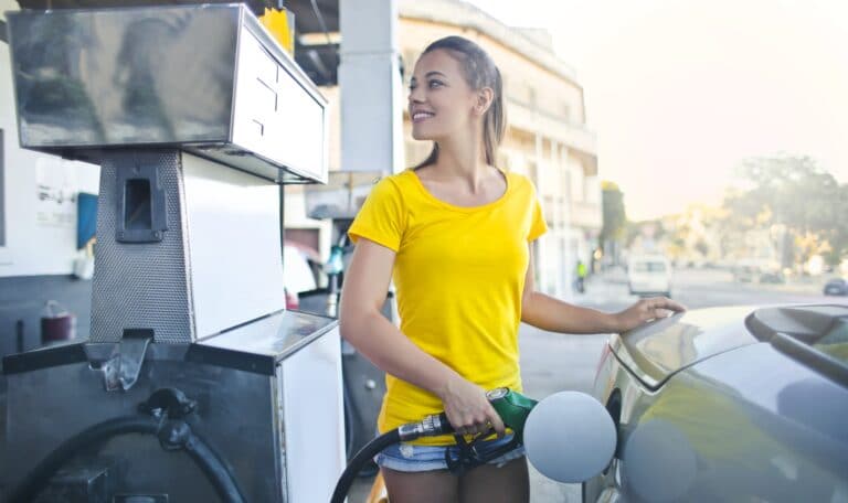 Woman in yellow shirt while filling up her car with gasoline