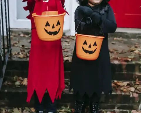 Crop children with buckets in halloween