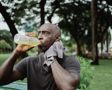 Man in Black Crew Neck T-shirt Drinking Yellow Liquid from Plastic Bottle