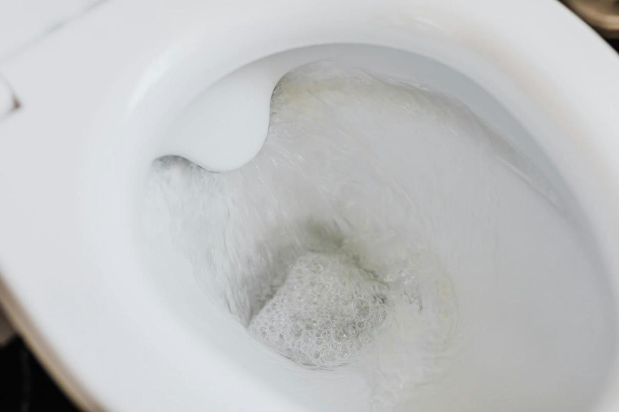 High-angle view of a toilet flushing with swirling water and bubbles, showcasing cleanliness.