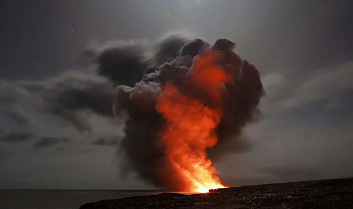 Volcanic eruption with smoke and lava under a starry night sky.