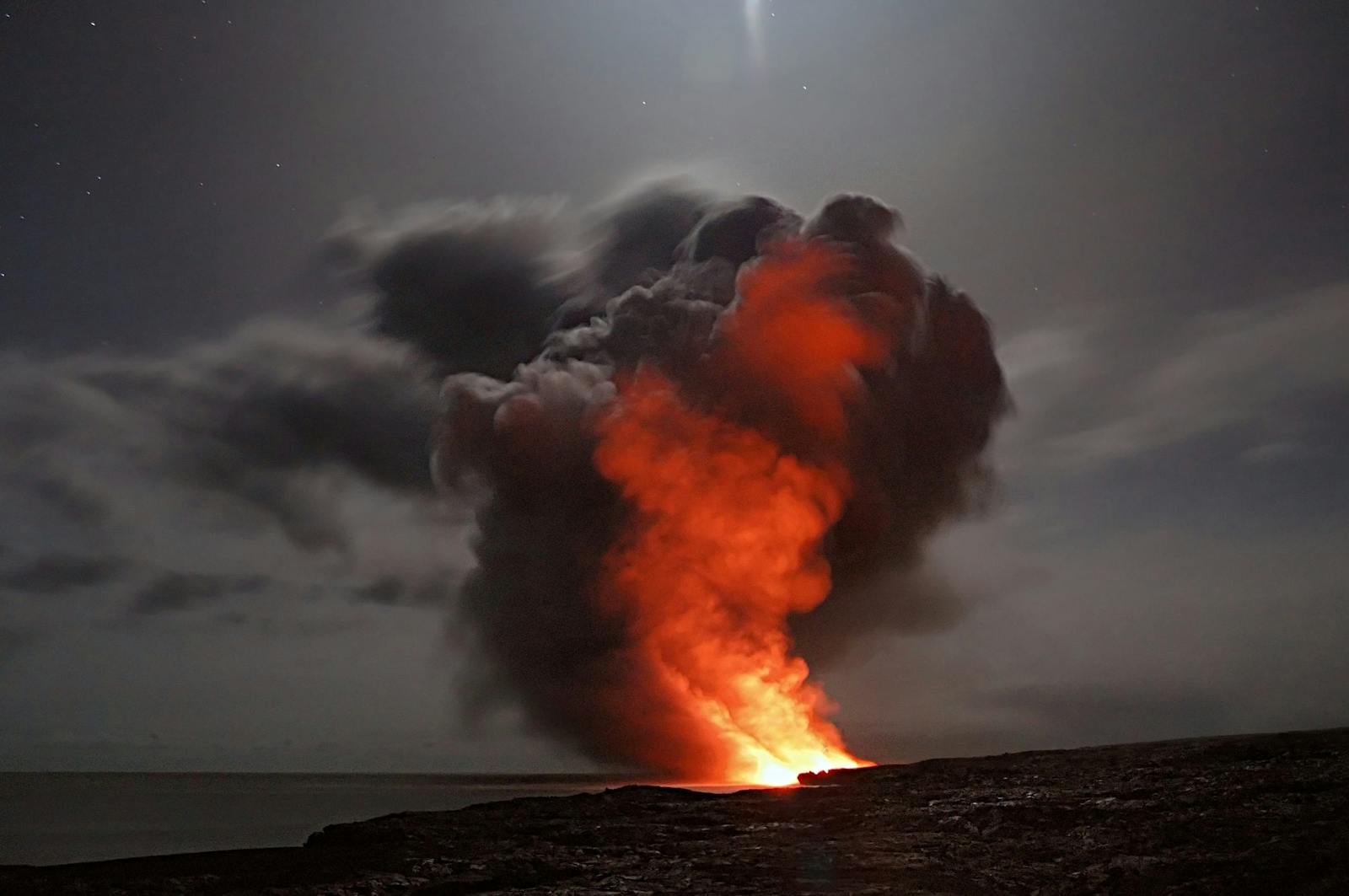 Volcanic eruption with smoke and lava under a starry night sky.