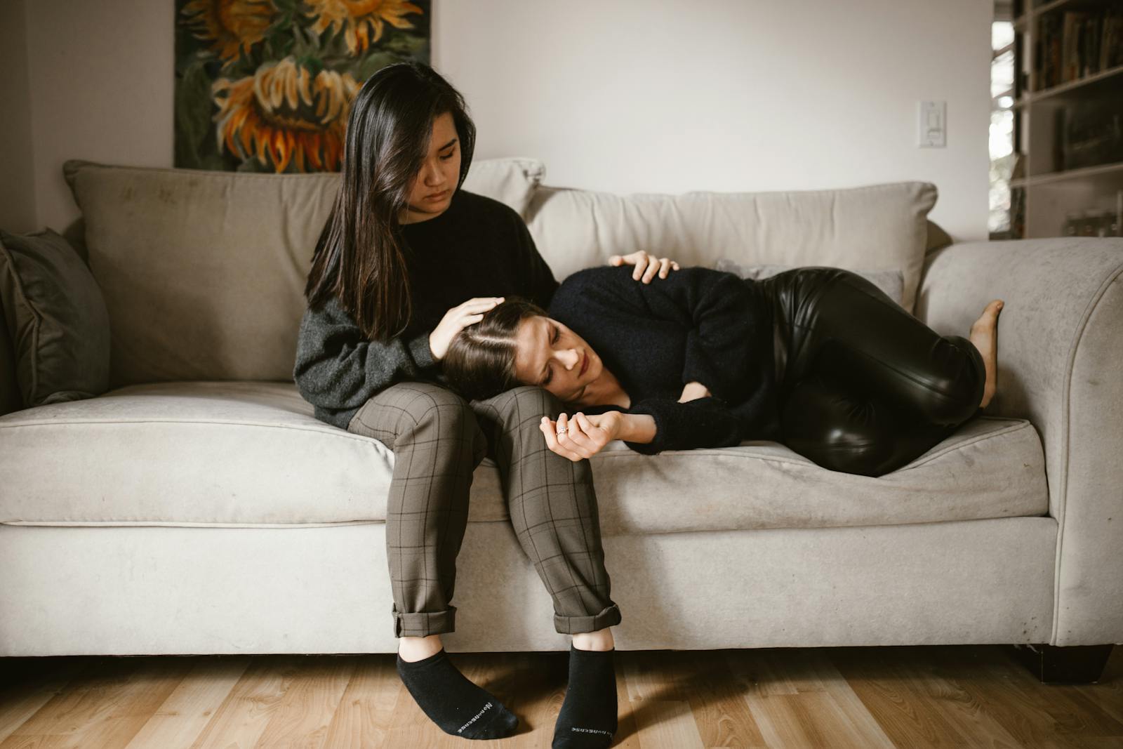 A comforting scene of empathy and support between two women sitting on a sofa indoors.