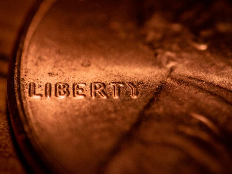 Macro photo of a copper penny highlighting the 'Liberty' inscription, focusing on texture and detail.