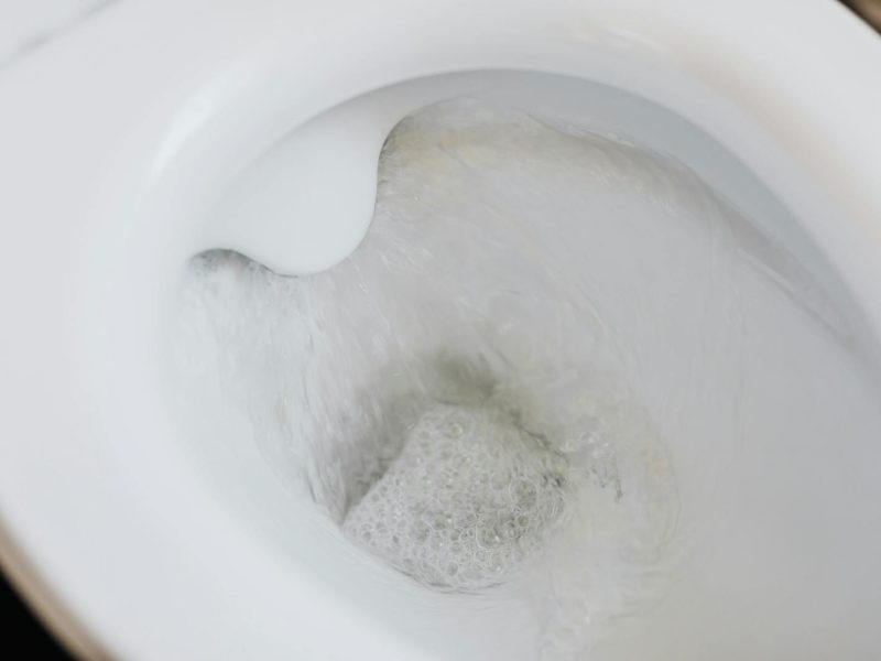 High-angle view of a toilet flushing with swirling water and bubbles, showcasing cleanliness.
