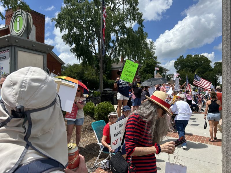 Thousands of “No Kings” protesters lined Main Street in Woodstock under a clear summer sky, holding signs bearing slogans like “We have a Constitution, not a King,” and “Morons are governing Amerikka,” and "America: No Kings Since 1776," a reflection of broader unease over what critics view as authoritarian posturing.