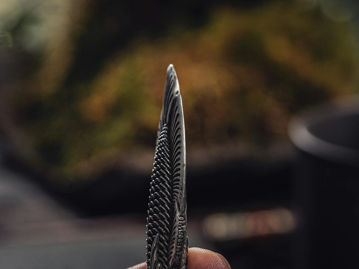 Detailed close-up of a fish-shaped steel box cutter, highlighting its cutting edge and intricate pattern.