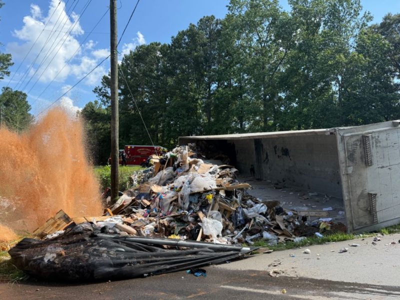 A garbage truck tipped over and struck a fire hydrant on East Cherokee Drive, forcing officials to close the road at Cokers Chapel Road.