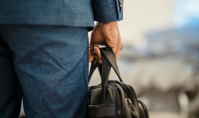 Close-up of a businessman's hand holding a briefcase, symbolizing professionalism.