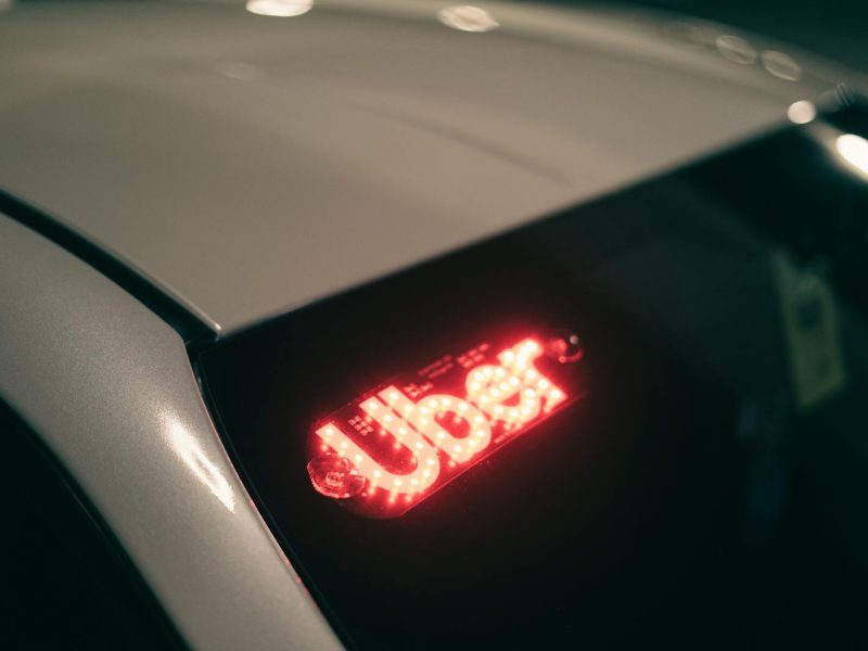 Close-up of a ride-sharing car with a bright red illuminated sign for night-time travel.