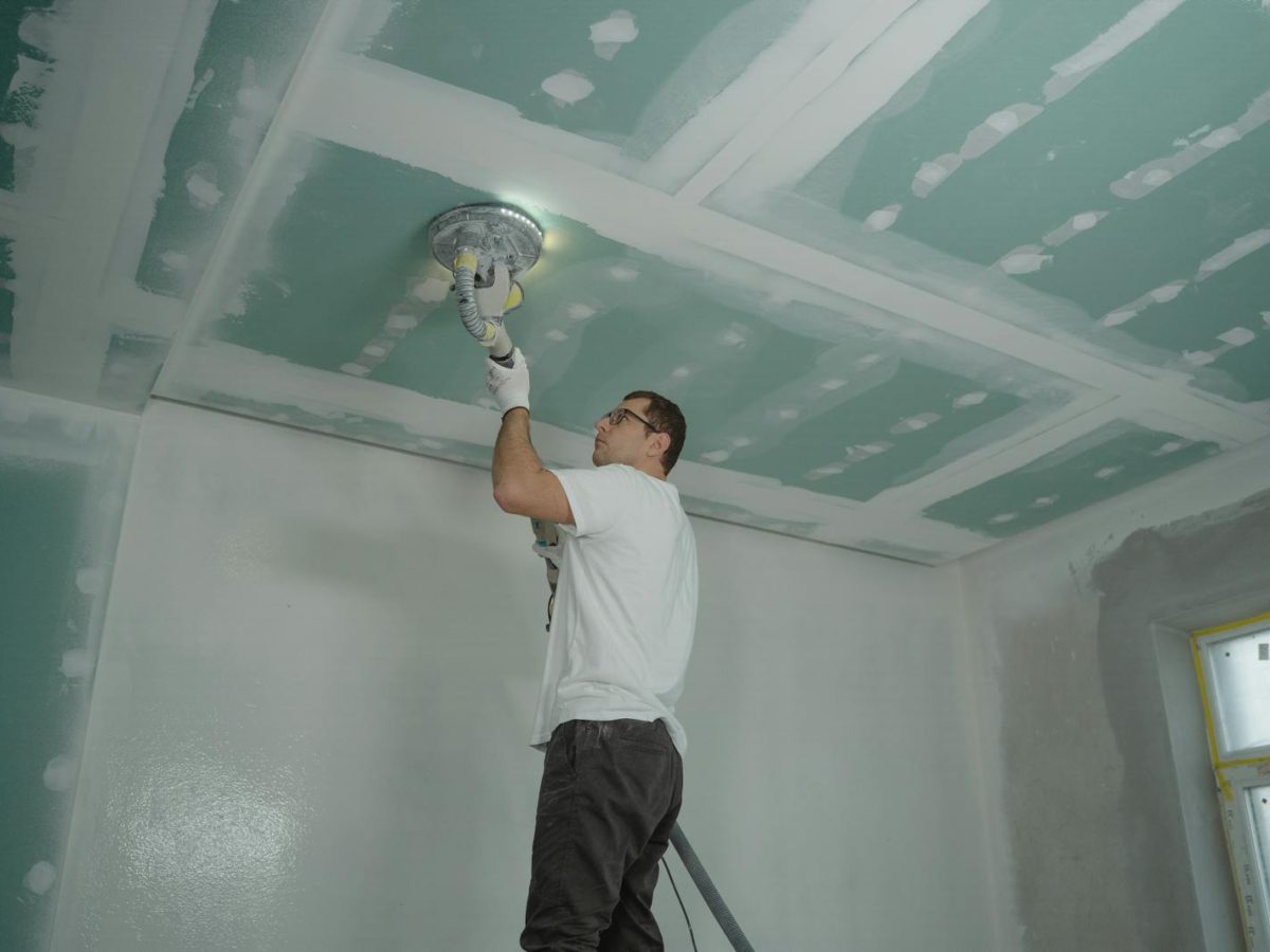 A worker expertly polishes a ceiling indoors, demonstrating home renovation skills.