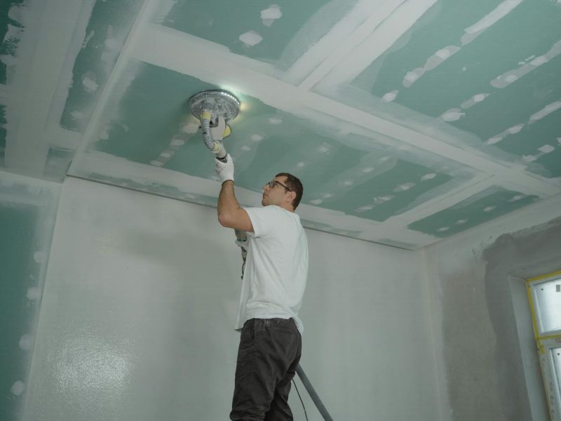 A worker expertly polishes a ceiling indoors, demonstrating home renovation skills.