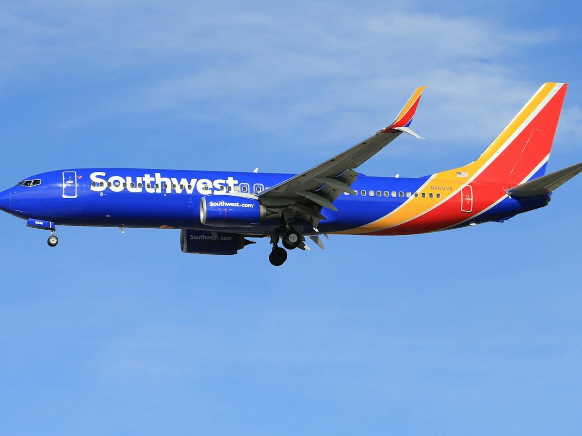 A vibrant Southwest Airlines airplane flying against a clear blue sky, showcasing its colorful livery.