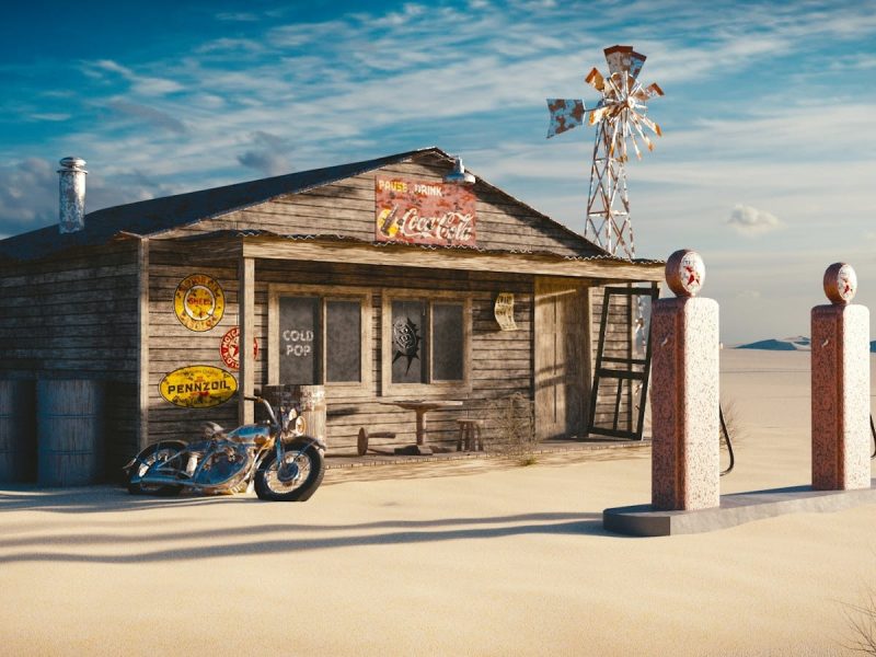 A vintage gas station in a desert setting, featuring a classic motorcycle and rustic signs.