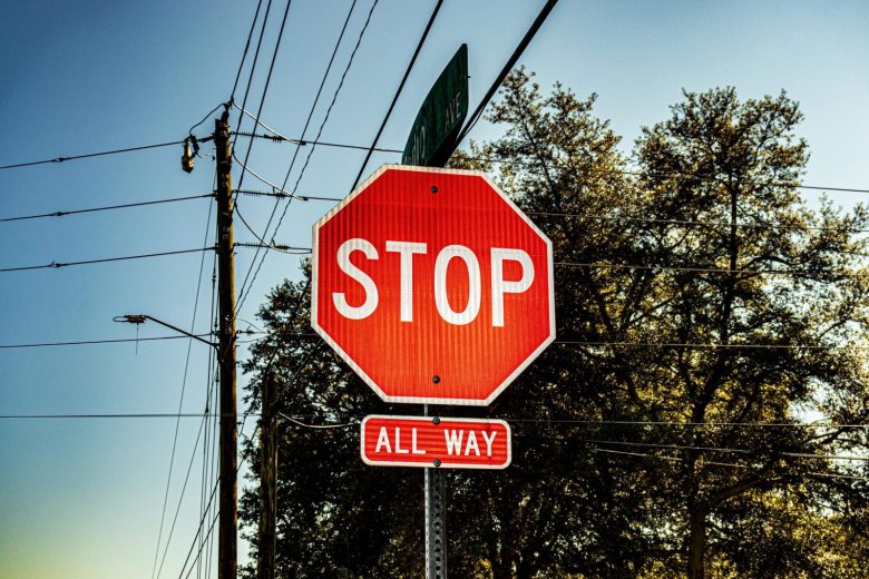 Bright red stop sign with all way label under a clear blue sky.