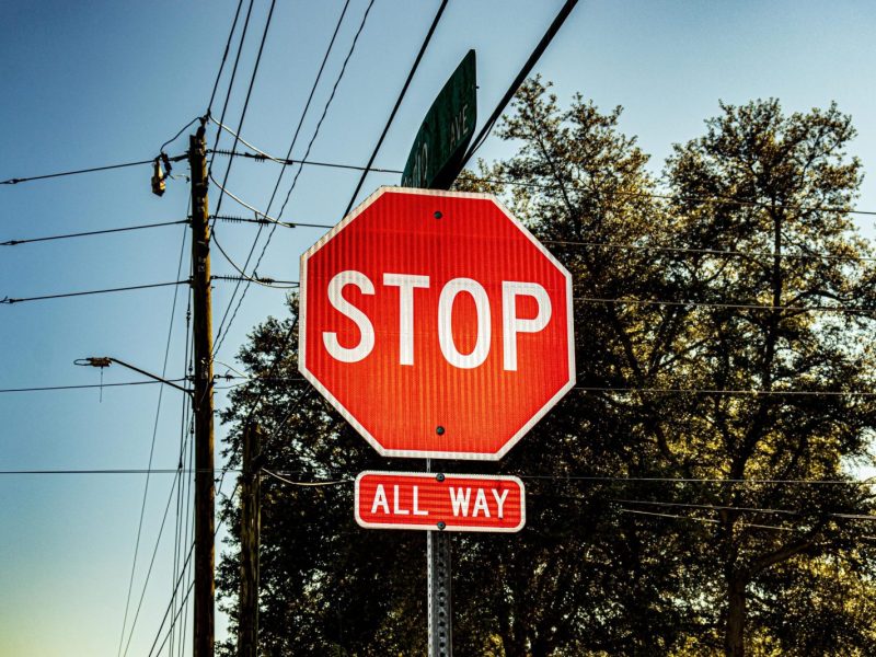 Bright red stop sign with all way label under a clear blue sky.