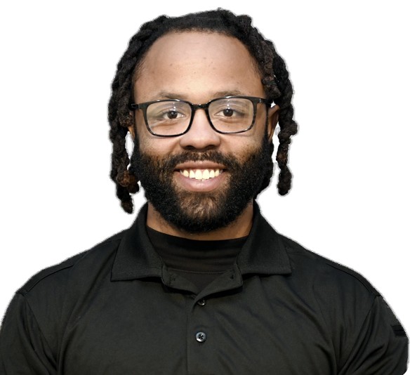 Man with medium-dark skin tone, wearing glasses and a black collared shirt, with short dreadlocks and a full beard, smiling.