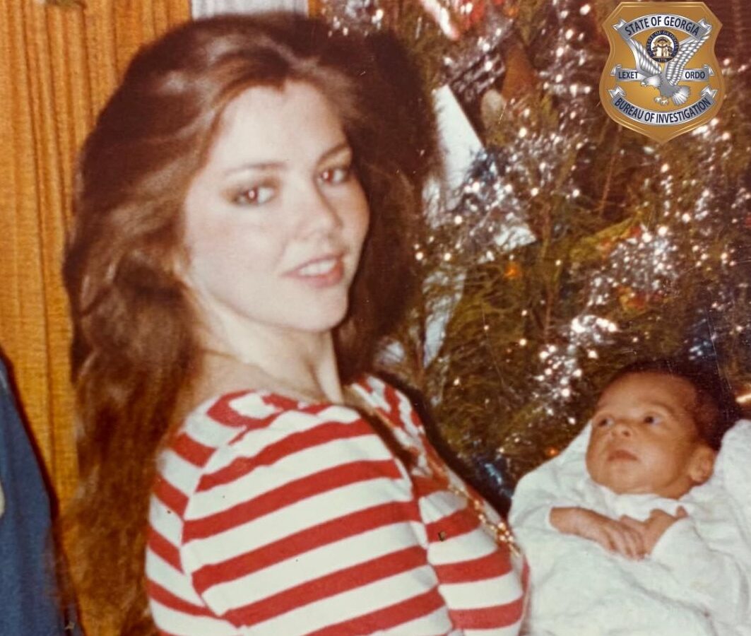 A woman with long brown hair wearing a red and white striped shirt is holding a baby wrapped in a white blanket. The background includes a decorated Christmas tree with tinsel. In the top right corner, there is a badge emblem that reads "State of Georgia Bureau of Investigation.