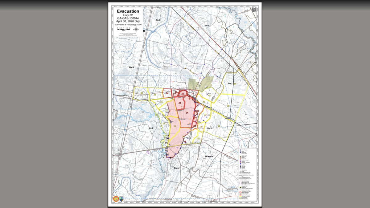 Map titled "Evacuation Hwy 82 GA-GAS-130044 April 30, 2026 Day," showing an evacuation area of 22,577 acres as of April 29, 2026, 2130 hours. The map highlights a central evacuation zone in shades of red and pink, bordered by yellow lines, with numbered sections within the zone. Surrounding areas are labeled with divisions such as Div I, Div J, Div G, Div L, Div M, Div E, Div A, and Branch I. Roads, water bodies, and other geographic features are marked, along with a legend in the bottom right corner indicating various symbols for properties, hazards, and infrastructure. The map includes a scale bar in miles and a north arrow for orientation.