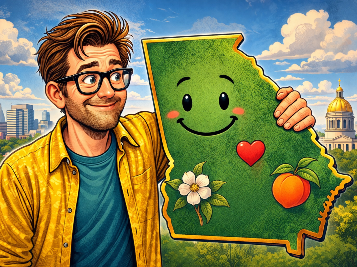 A smiling man with glasses and tousled brown hair, wearing a yellow patterned shirt over a blue t-shirt, is holding a large, cartoonish green map of Georgia. The map has a happy face, a red heart, a white flower, and a peach illustrated on it. In the background, there is a cityscape with tall buildings and a domed golden-roofed building, set against a blue sky with fluffy clouds.