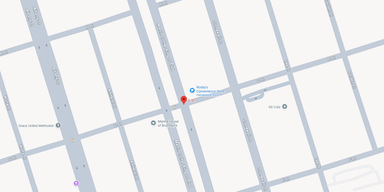 Map showing the intersection of G St and Martin Luther King Jr Blvd, with nearby streets including Albany St, Amherst St, Stonewall St, Lee St, Gordon St, Wolfe St, and H St. Notable locations marked are Rosby's Convenience Store, Manna House of Brunswick, Grace United Methodist, and G6 Cutz. Traffic lights are indicated at some intersections.