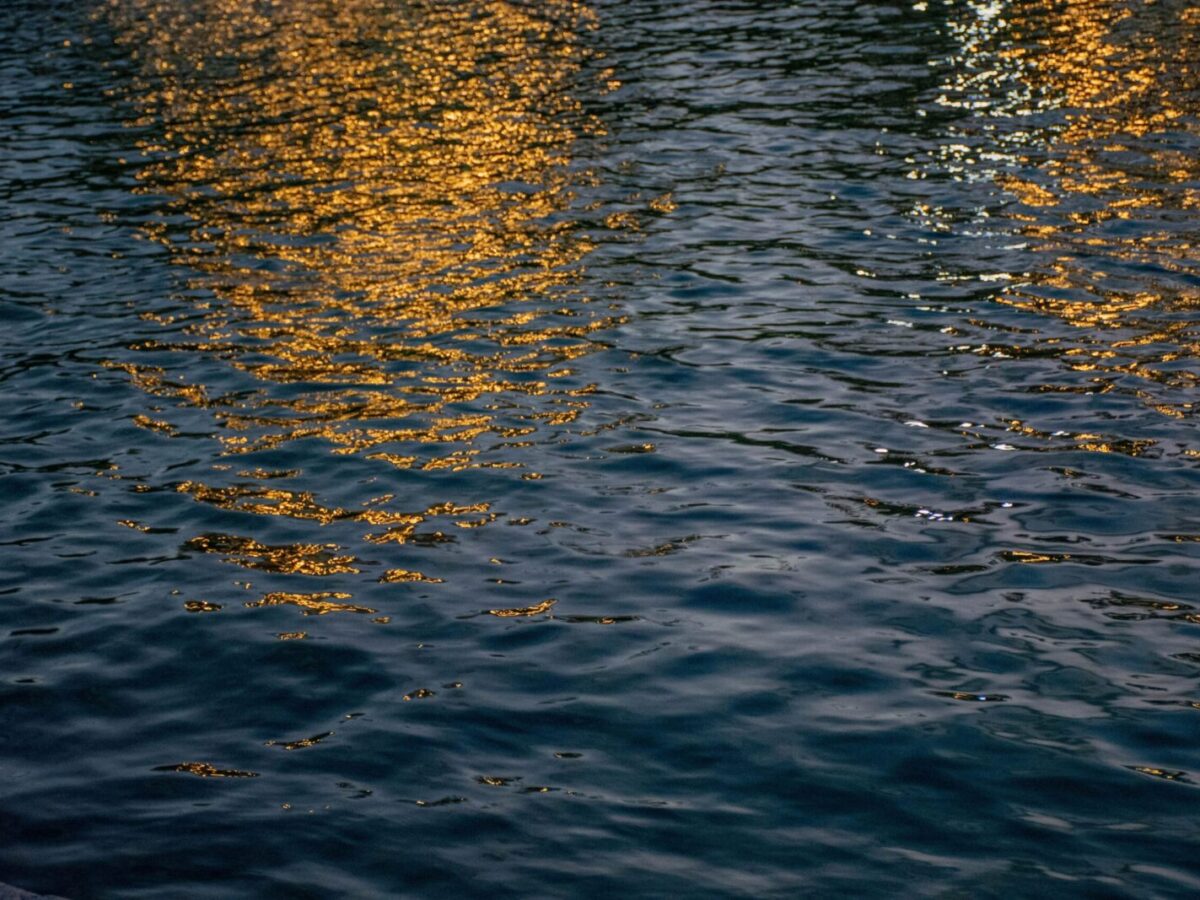 Evening lights reflecting on a tranquil water surface, creating a serene golden glow.