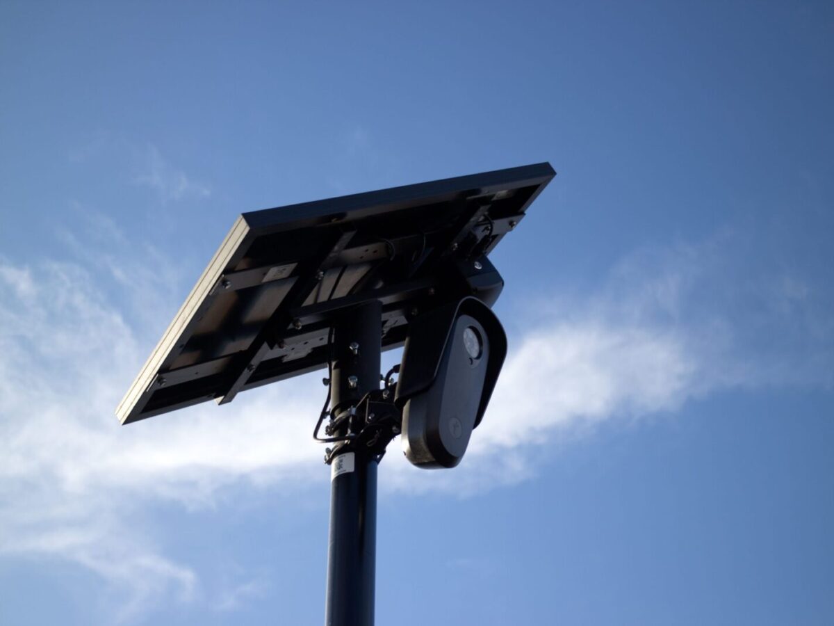 Solar-powered CCTV camera mounted on pole with bright sky background, symbolizing security and technology.