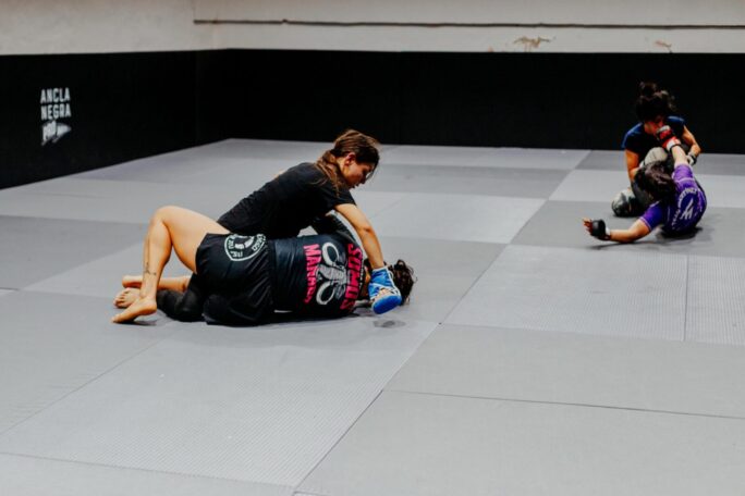 Female martial artists training at a gym in Buenos Aires, showcasing skill and strength.